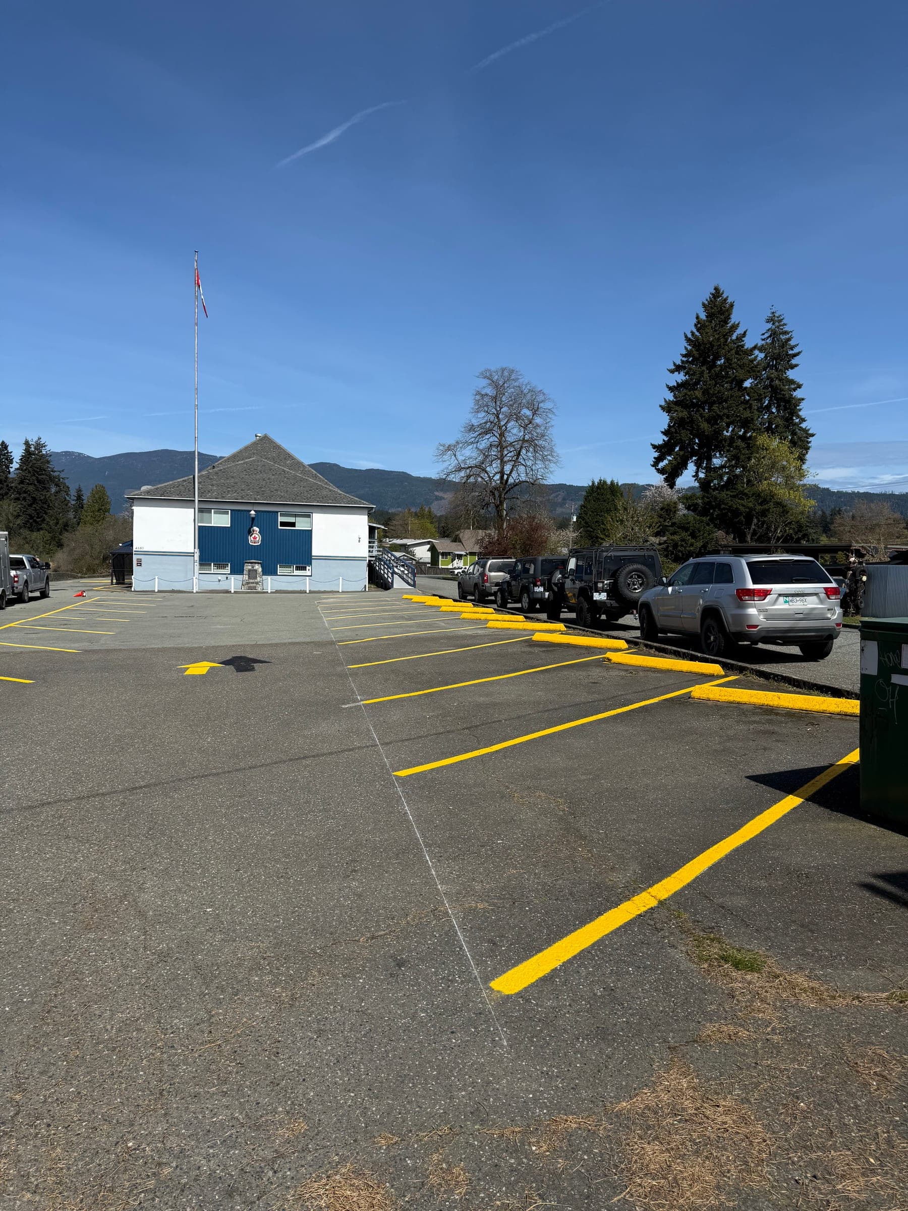 After photo of freshly painted yellow parking lines beside a blue building.